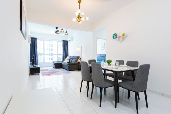 A modern living room with a dining area, large windows, and a grey sofa.