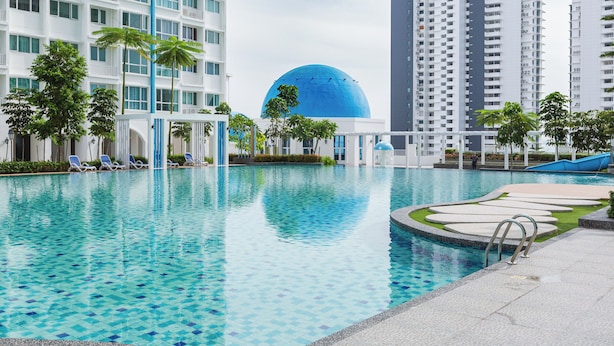 A swimming pool with lounge chairs, palm trees, and a large blue dome structure. - Pool View 3BR* Walk to SHOPS EAT * AC & Wi-Fi (Tanjung Tokong)