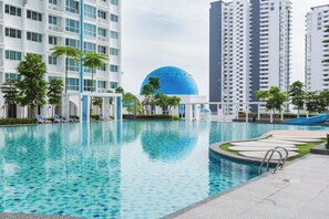 A swimming pool with lounge chairs, palm trees, and a large blue dome structure. - Pool View 3BR* Walk to SHOPS EAT * AC & Wi-Fi (Tanjung Tokong)