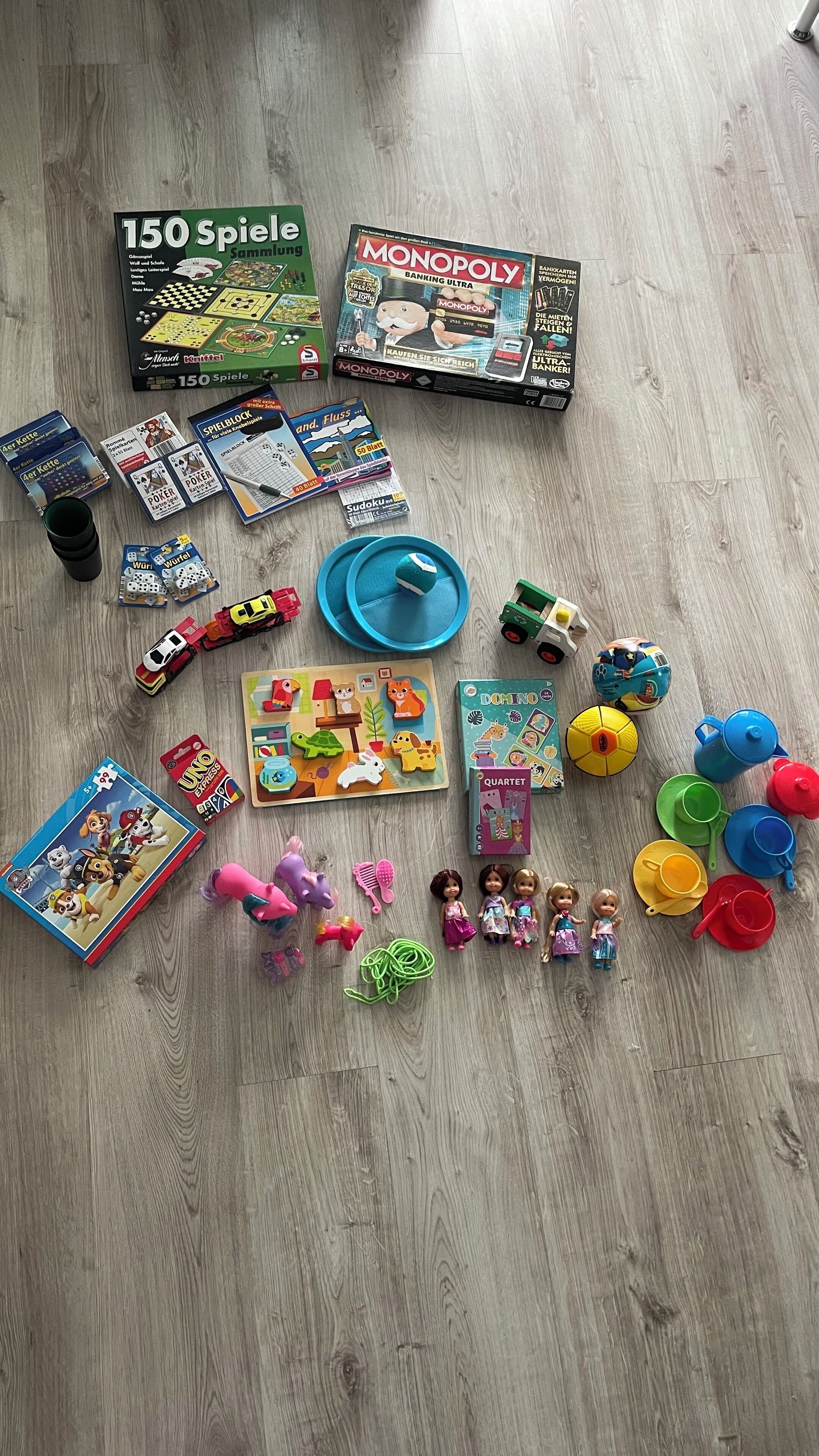 A variety of board games and toys spread out on a wooden floor.
