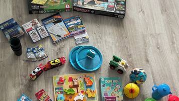 A variety of board games and toys spread out on a wooden floor.