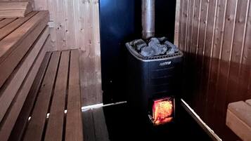 A sauna with a black heater and a visible firebox.