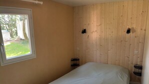 A bedroom with a large bed, a window with a view of the outside, and two wall-mounted nightstands. - Renovated mobile home bathroom with Italian shower (Gavaudun)