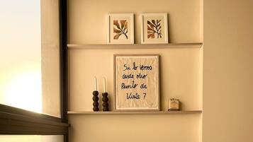A neutral-toned sofa with a cushion, a framed quote on the wall, and two framed leaf designs.