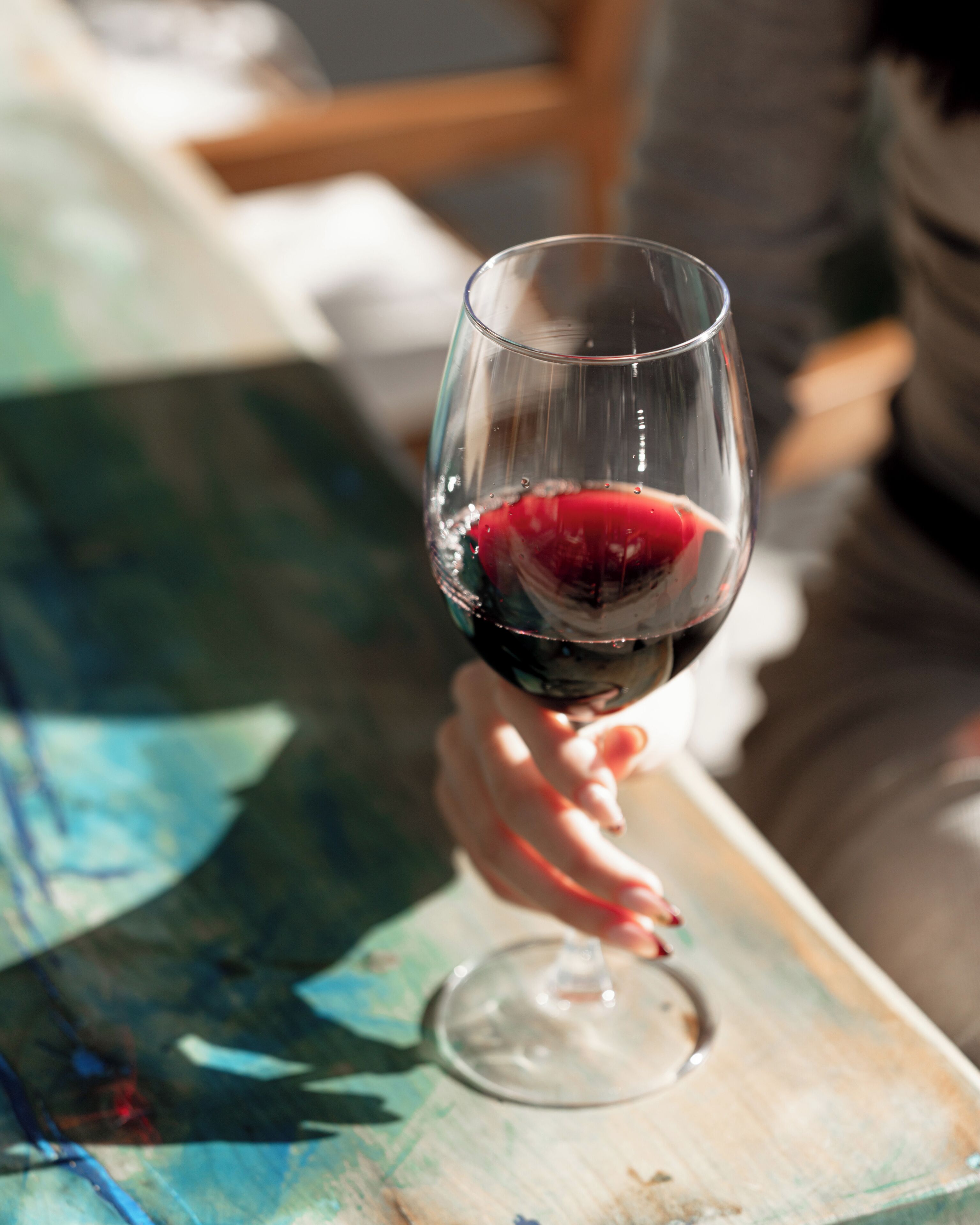 A clear glass of red wine on a wooden table.