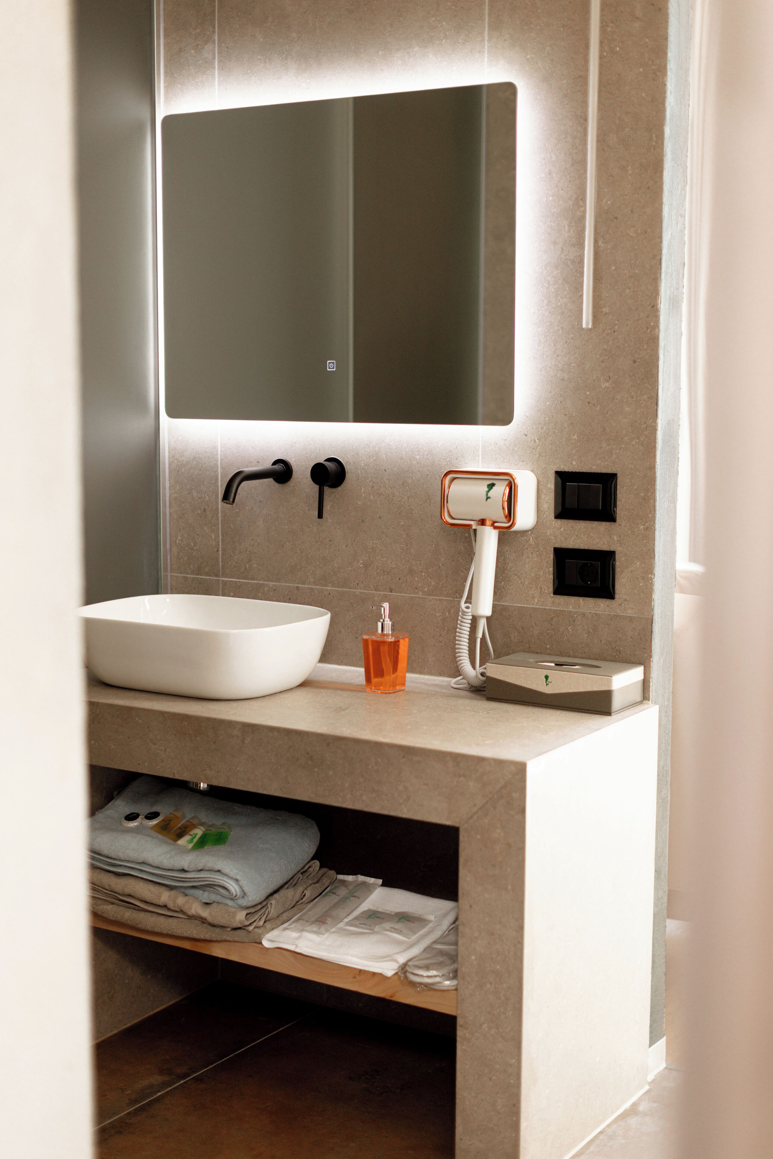 A modern bathroom with a large white sink, a mirror above it, and a towel rack below.