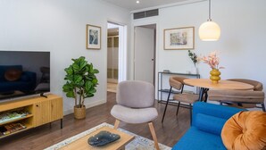 Ein modernes Wohnzimmer mit Fernseher, Sofa und Essbereich.