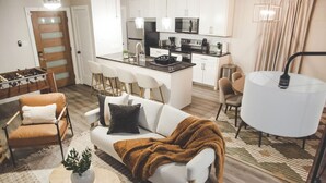 A modern living room with a sofa, chairs, a coffee table, and a dining area with a table and chairs. - Fort Worth 2BR/2BA Home w/ Pool + Games | Sleeps 6 (Fort Worth)