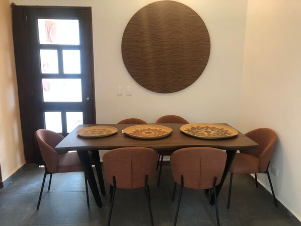 A dining area with a rectangular table, six chairs, and a decorative wall piece.