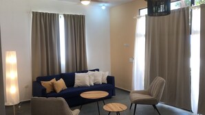 A living room with a blue sofa, two armchairs, a round wooden coffee table, and a floor lamp. - Casa Playa Rincon Hills Samana (Samaná)