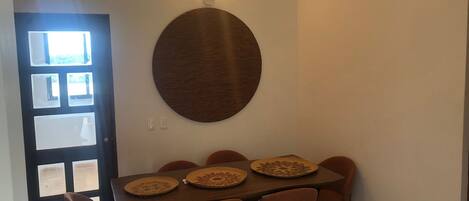 A dining area with a round wooden table, six chairs, and a ceiling fan.