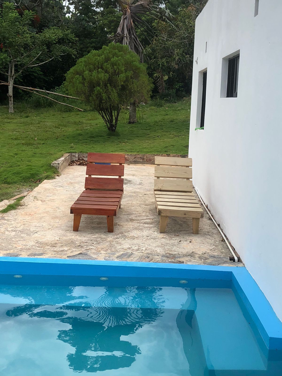 Un espace piscine avec deux bancs en bois et un bâtiment blanc en arrière-plan.