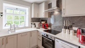 A modern kitchen with white cabinets, a black stovetop, and a window providing natural light.