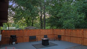 An outdoor patio area with a fire pit, seating, and a barbecue grill, surrounded by a wooden fence and trees. - Peaceful 3-bedroom house in Valliant! Close to International Paper and PineCreek (Valliant)