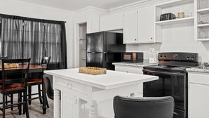 A kitchen with white cabinetry, a black stove, and a dining area with a white table and chairs. - Peaceful 3-bedroom house in Valliant! Close to International Paper and PineCreek (Valliant)
