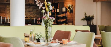 Un comedor con una mesa de madera dispuesta para dos personas, rodeada de sillas verdes.