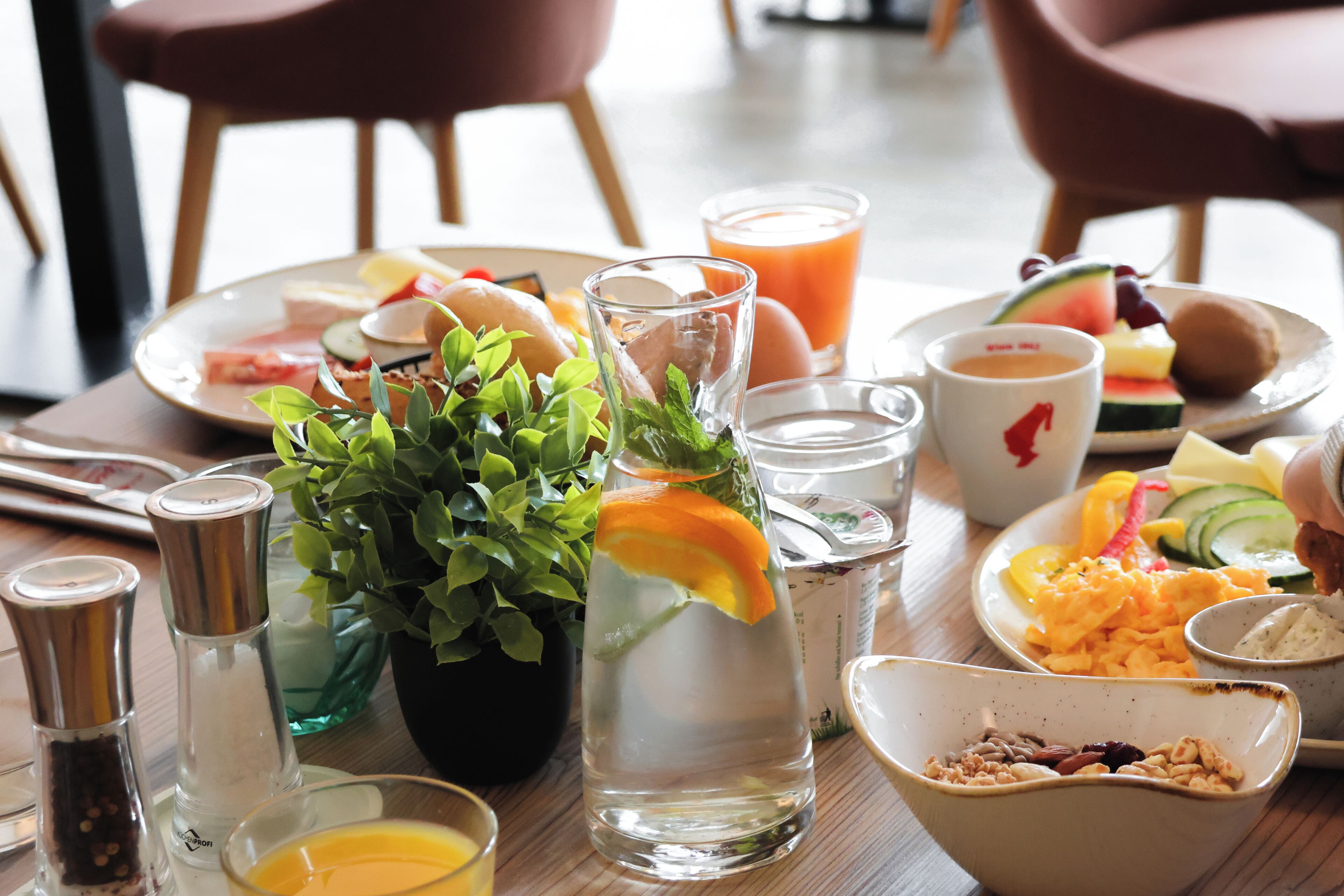 A dining table with various food items, a glass of water, and a potted plant.