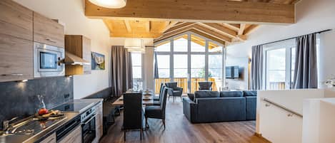 Une cuisine moderne avec un coin repas, un plancher en bois et de grandes fenêtres.