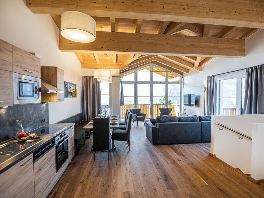 Una cocina moderna con comedor, piso de madera y amplios ventanales.