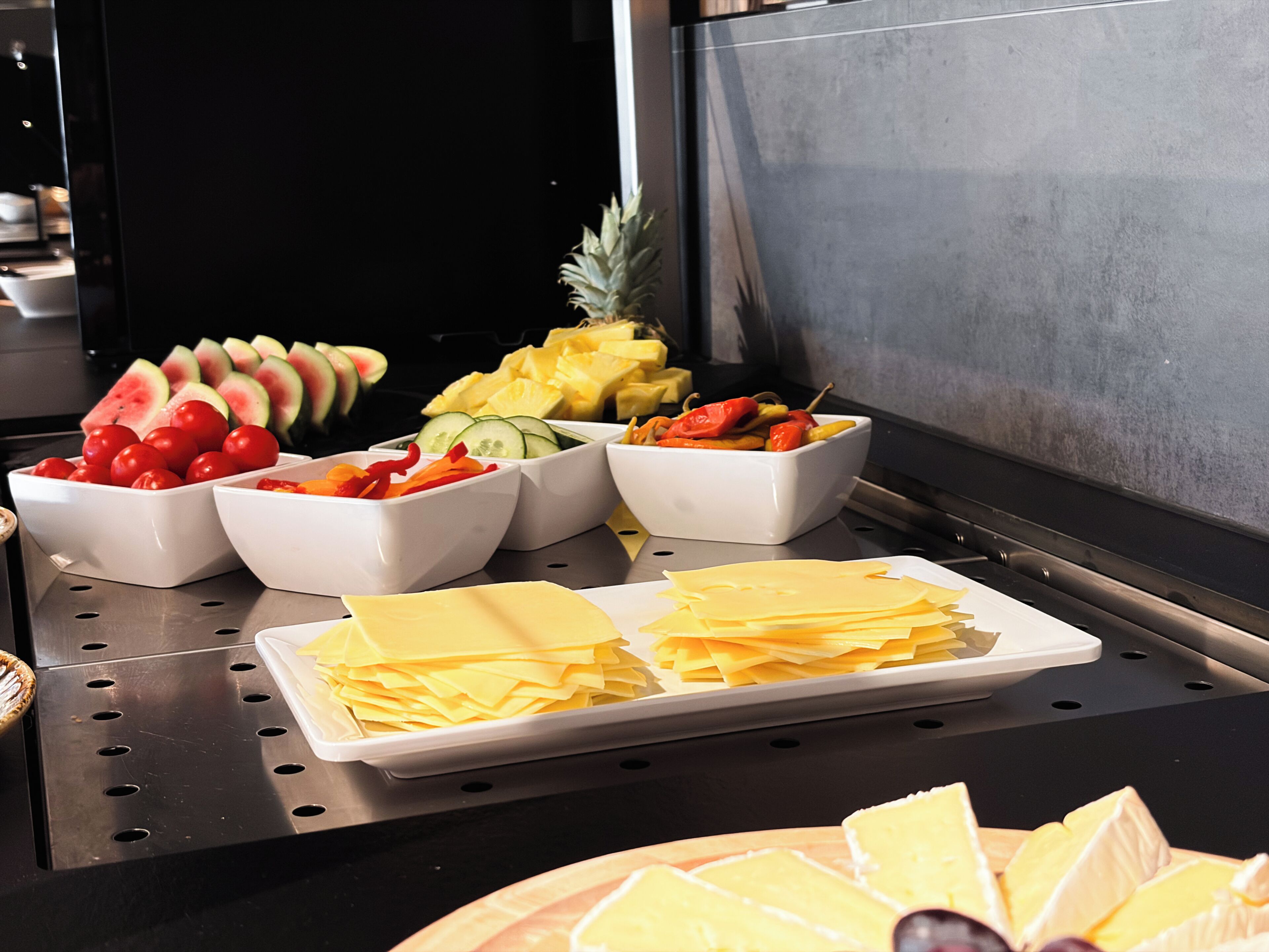 A buffet table with various food items including fruits, vegetables, and cheese.