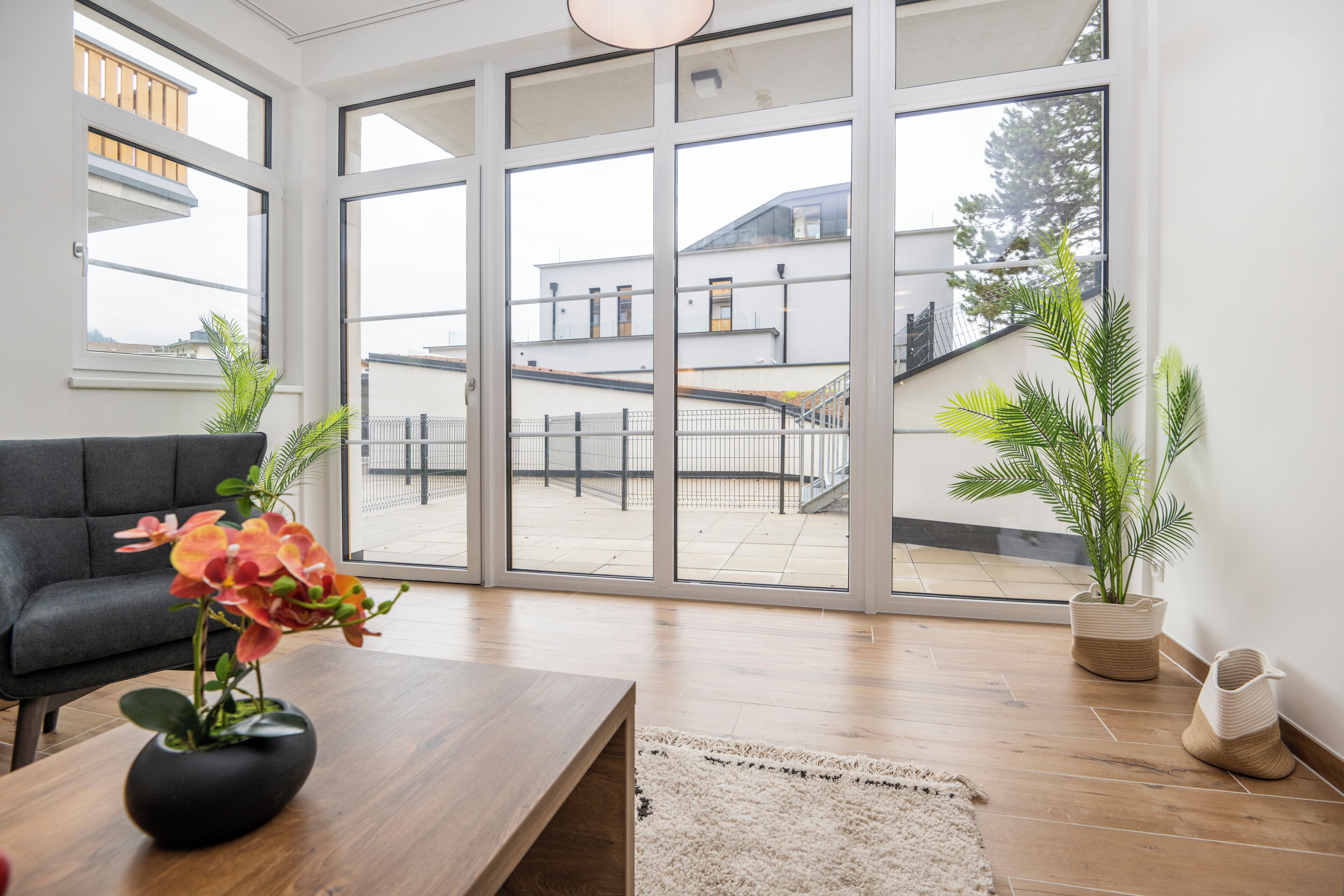 A modern living room with a large sliding glass door leading to an outdoor balcony.