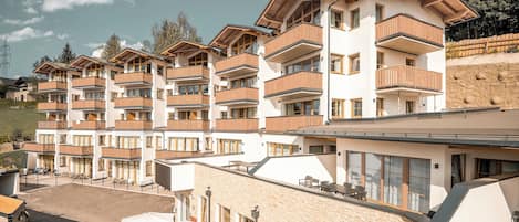 A multi-story hotel with balconies, outdoor seating, and a ski slope in the background.