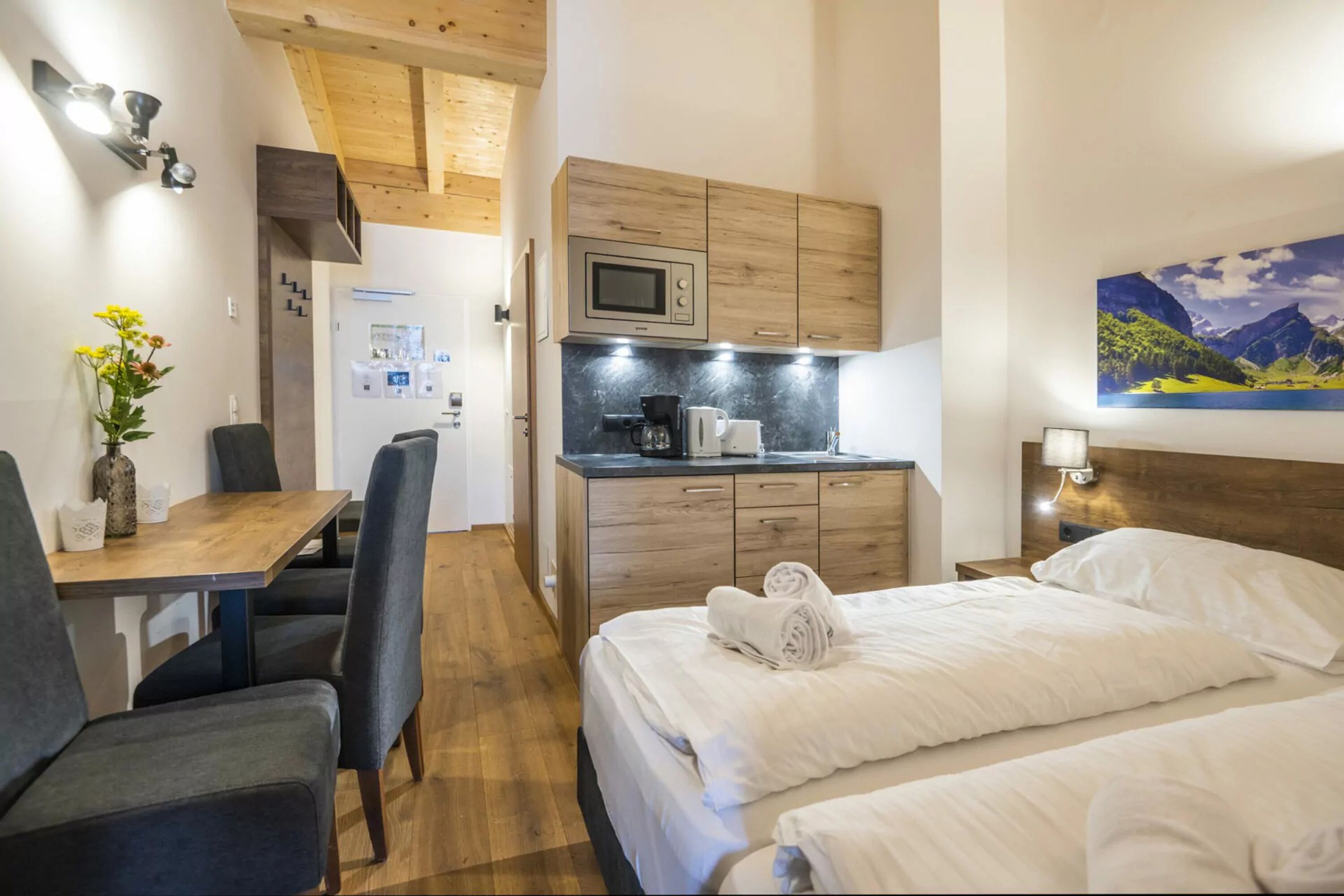 Une chambre d’hôtel compacte comprenant un coin cuisine, un espace repas et un lit.