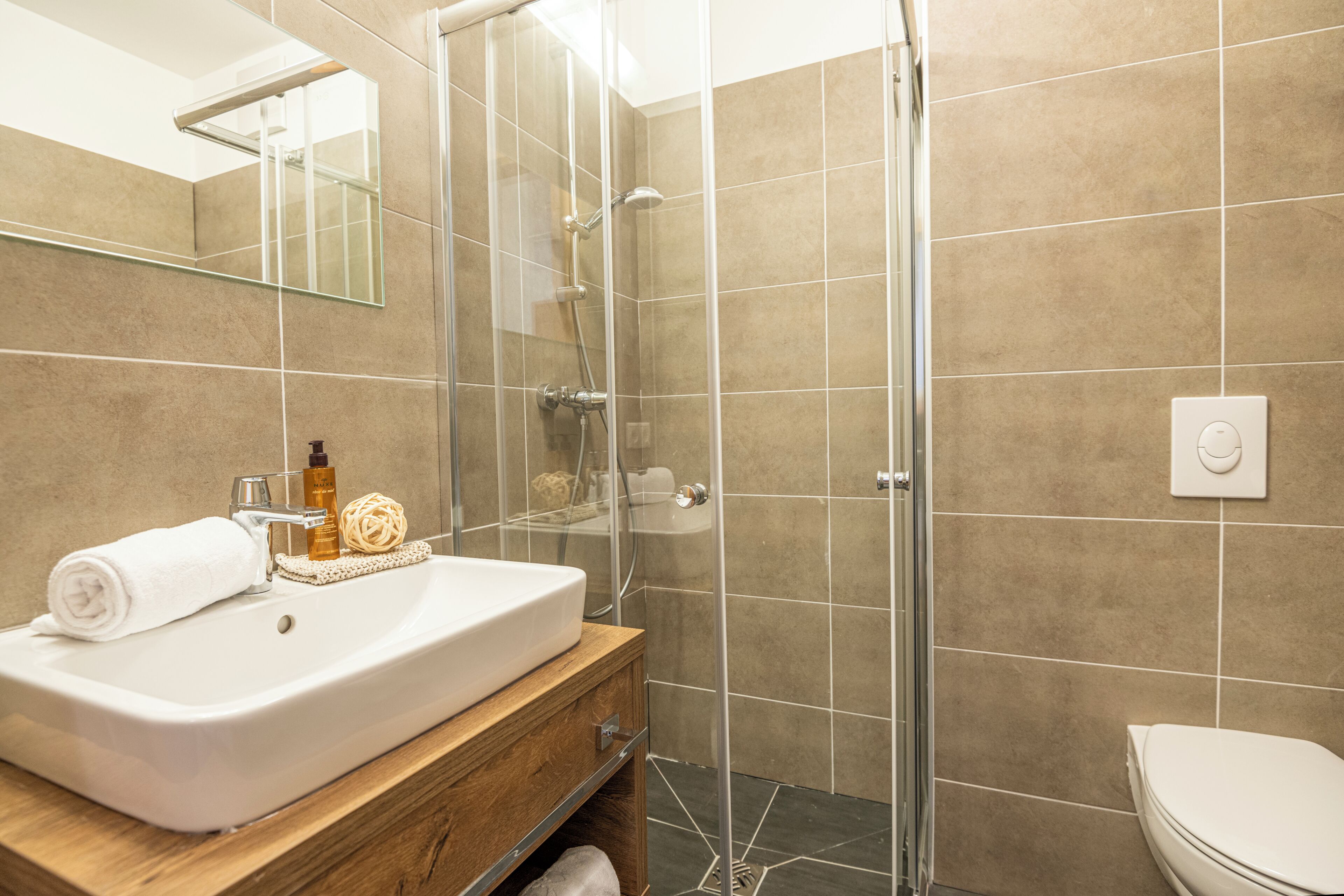 A bathroom with a glass-enclosed shower, a white sink, and a toilet.