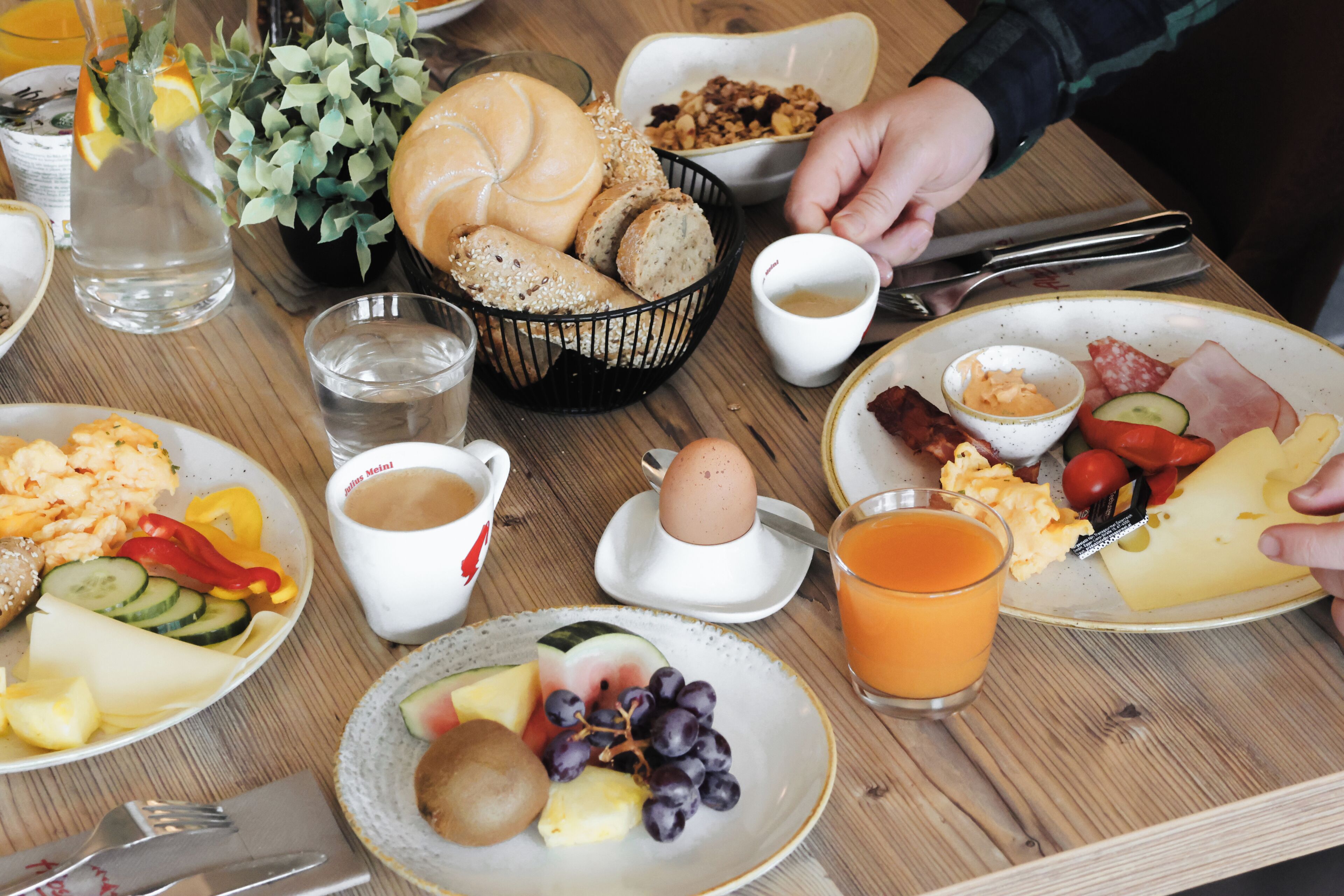 A breakfast table with various food items, including eggs, bread, and fruit.