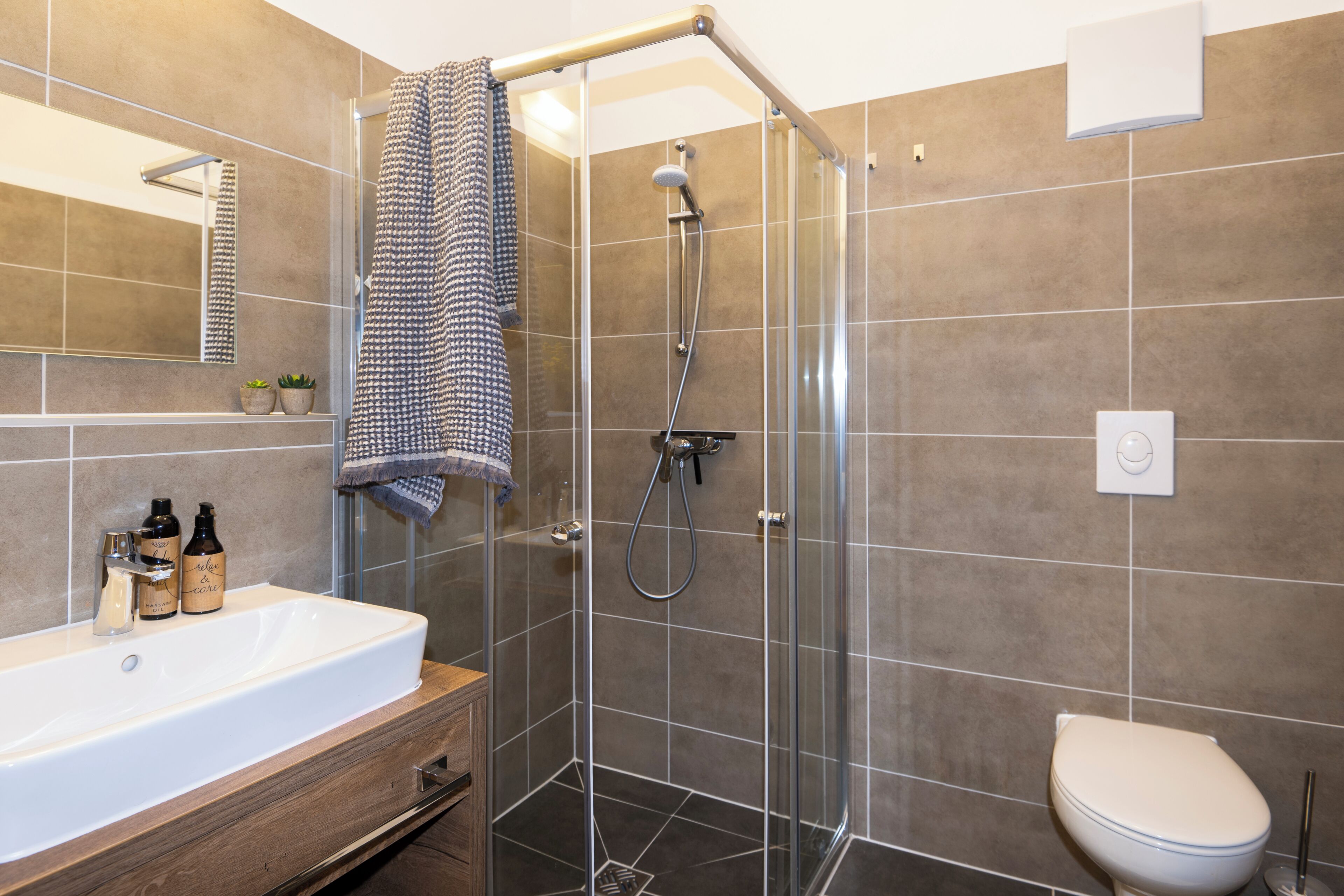 A modern bathroom with a glass-enclosed shower, a white sink, and a toilet.