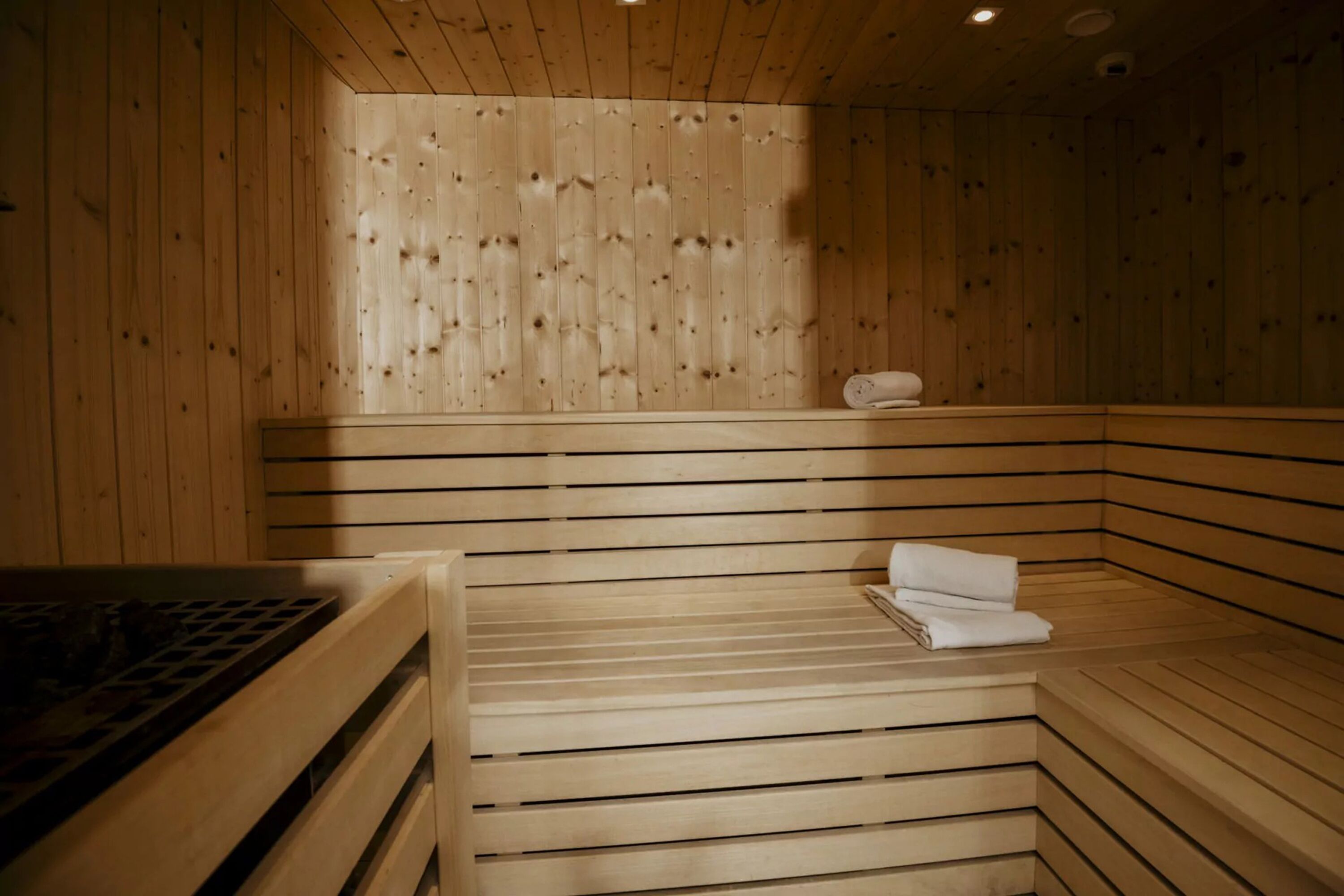Una sauna con paredes y bancos de madera, un perchero y un banco con una toalla.
