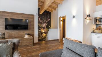 Ein modernes Wohnzimmer mit Flachbildfernseher, Holzboden und Dekoration aus Hirschgeweihen.