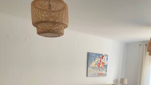 A dining area with a table and chairs, a sofa, and a painting on the wall. - Bright & Spacious 3-Bed Apartment - Pool, Garden, AC, Walk to Beach, Golf 5 Mins (Lagos)