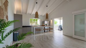 A modern kitchen with white cabinetry, a central island, and hanging woven light fixtures. - Villa Gone Coco - Coral Estate Resort (Sint Willibrordus)