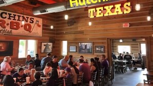 Un interior de restaurante con paredes de madera y un techo alto, con varias mesas y sillas para comer.