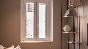 A modern living room with a sofa, a coffee table, a bookshelf, and a window with blinds. - Kira Central Hvar (Hvar)