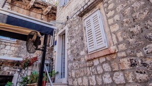 A stone building with a staircase leading to a door, surrounded by other buildings. - Kira Central Hvar (Hvar)
