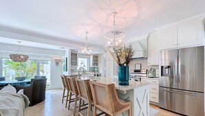 A modern kitchen with a central island, stainless steel appliances, and a dining area with a view of the outdoors. - Siesta Key Oasis-Spectacular with heated pool/spa and steps to beach and Village (Siesta Key)