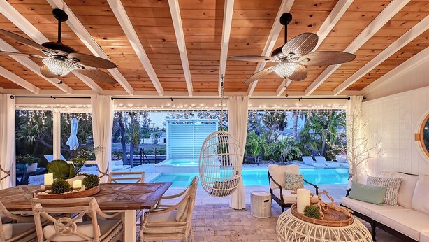 A wooden ceiling with ceiling fans, a pool, wicker furniture, and a white sofa. - Siesta Key Oasis-Spectacular with heated pool/spa and steps to beach and Village (Siesta Key)