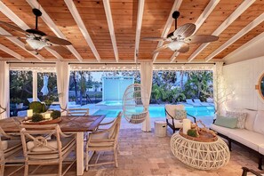 A wooden ceiling with ceiling fans, a pool, wicker furniture, and a white sofa. - Siesta Key Oasis-Spectacular with heated pool/spa and steps to beach and Village (Siesta Key)