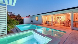 A modern house with a swimming pool, a dining area with outdoor seating, and a well-lit interior. - Siesta Key Oasis-Spectacular with heated pool/spa and steps to beach and Village (Siesta Key)