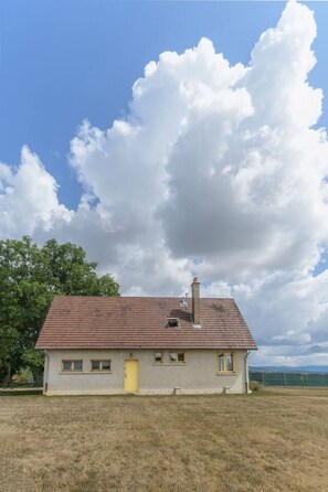 A single-story house with a red-tiled roof, a chimney, and a small porch.