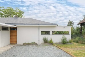 Een modern gelijkvloers huis met een schuin dak, een houten deur en een klein portaal.