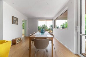 Een moderne eetruimte met een houten tafel, stoelen en een blauwe vaas als middelpunt.