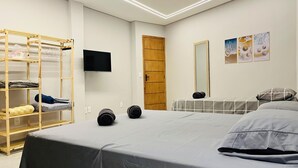 Een slaapkamer met een bed, een houten schapunit, een televisie, een spiegel en kunst aan de muur.