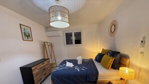 A bedroom with a bed, bedside table, lamp, wardrobe, and a hanging light fixture.