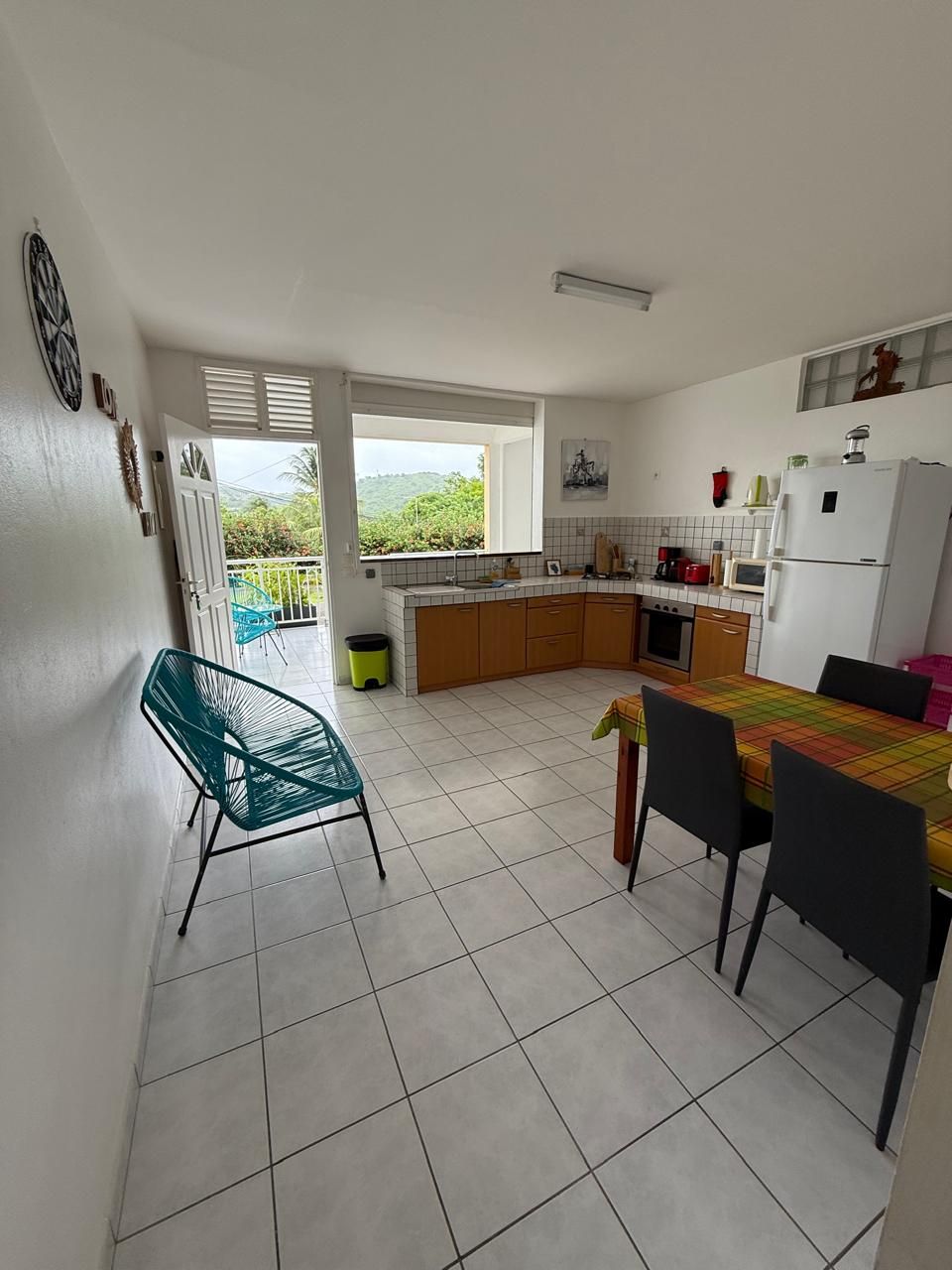 A kitchen with a dining area, a view of greenery outside, and a balcony.