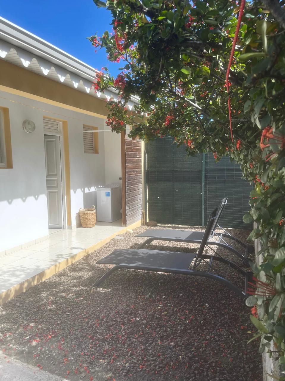 Un espace extérieur abrité, doté d’une terrasse, d’une chaise en métal et d’une petite table.