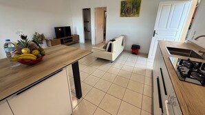 A modern kitchen with a central island, a dining area with a sofa, a TV, and a painting on the wall.