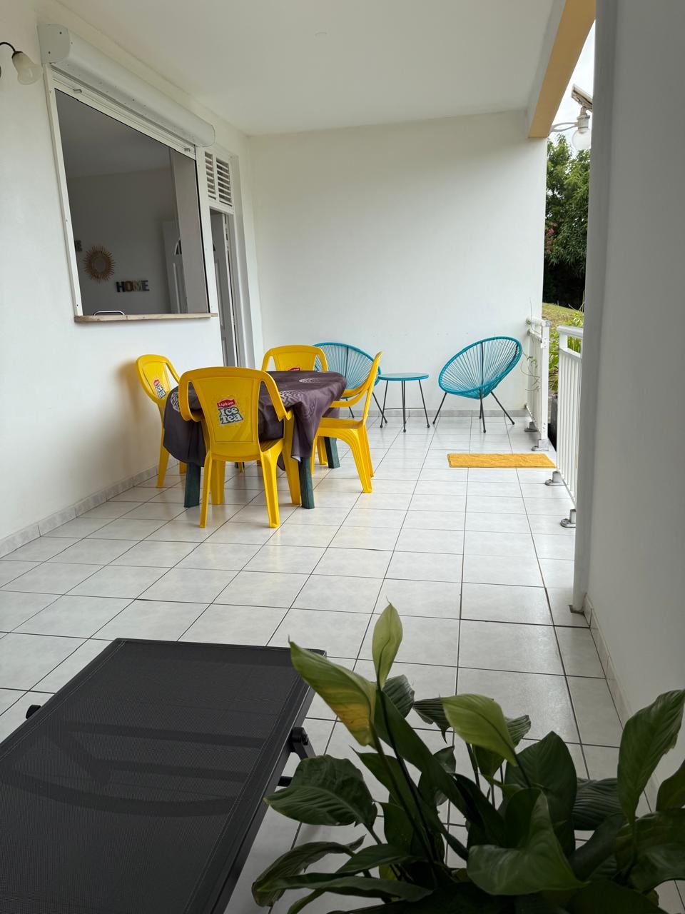 Ein Balkon mit Tisch, Stühlen und einer Topfpflanze, mit Blick ins Freie.